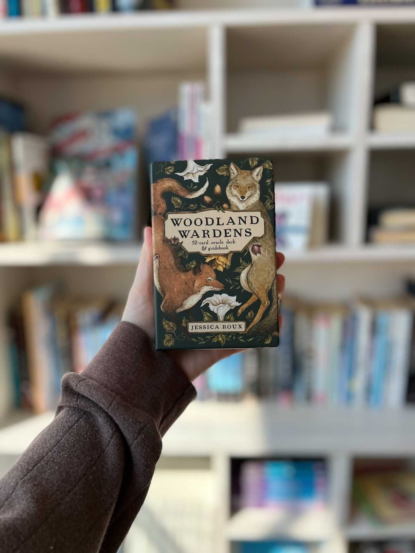 Book titled 'Woodland Wardens' held in front of a bookshelf.